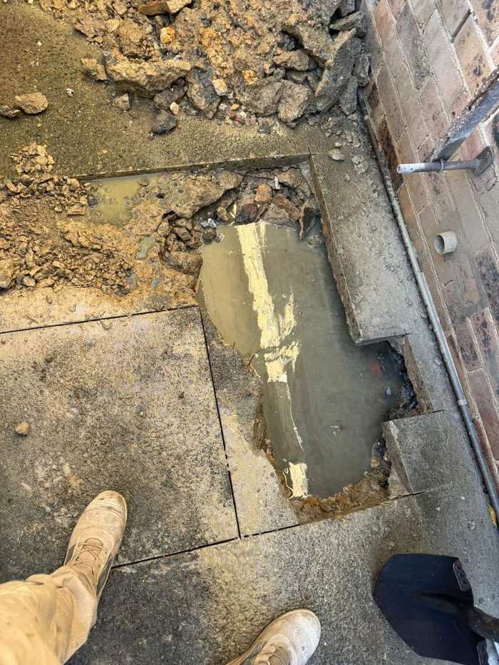 Excavated concrete path revealing a drainage leak