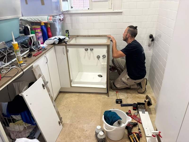 Vanity cabinet being fitted and plumbed in
